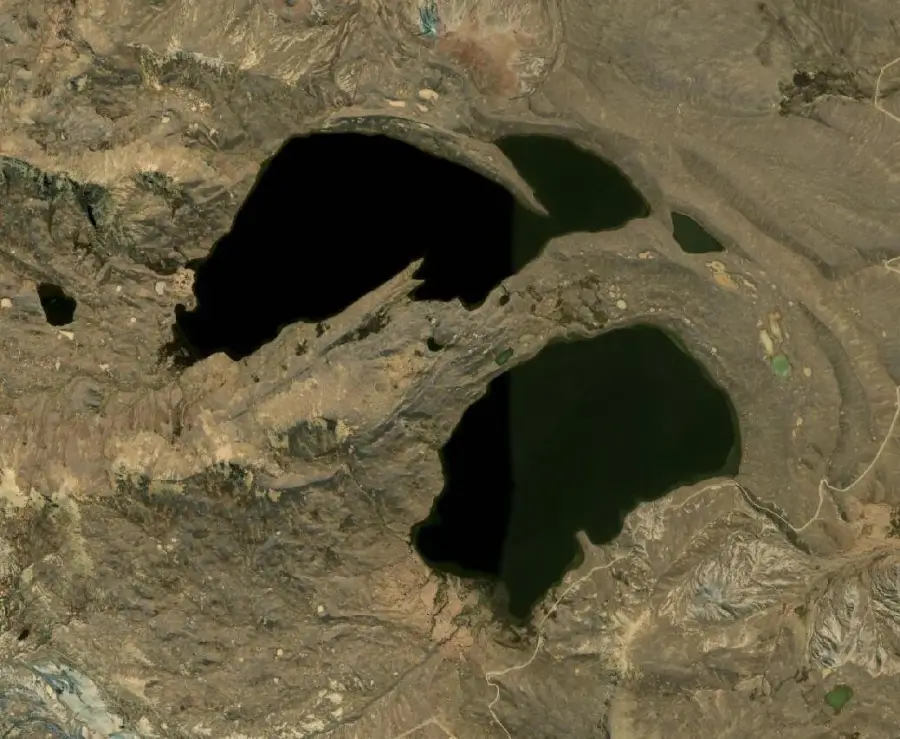 Suite de lacs noirs au milieu d'une zone de cailloux formant un visage de souffrance, hurlant en silence